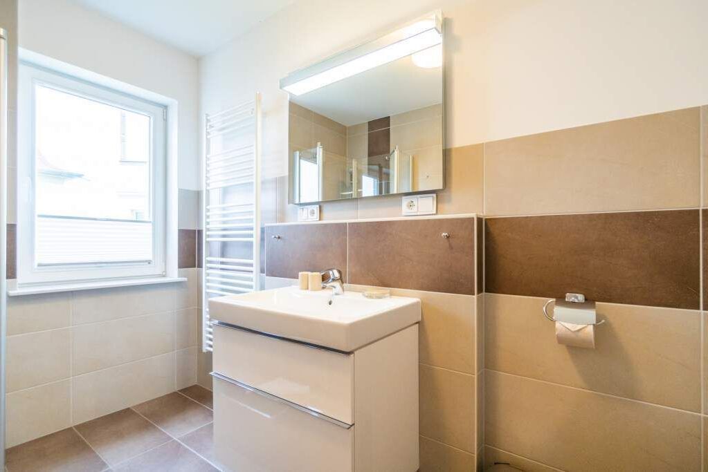 A bathroom with a white sink, a mirror, and a towel rack.