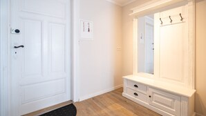 Um quarto com porta branca, um espelho grande sobre uma cômoda, e um interruptor de luz na parede.
