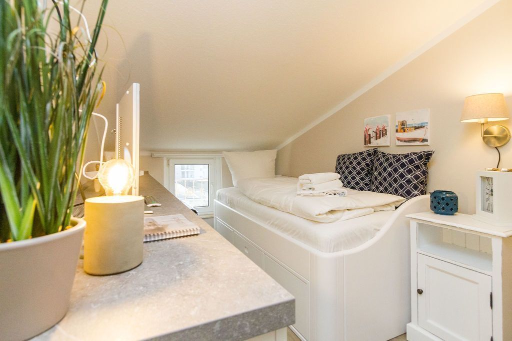 Een compacte, goed verlichte kamer met een bed, nachtkastje en een klein kastje.