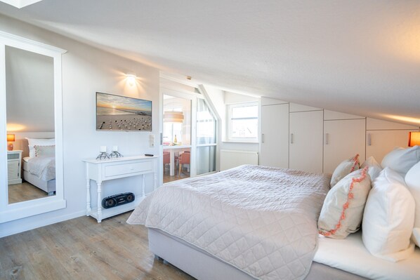 Ein Schlafzimmer mit einem großen Bett, einem Schminktisch, einem Spiegel und einem Schreibtisch mit Stuhl.