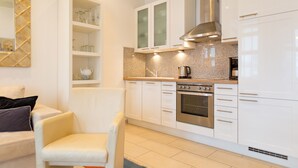A modern kitchen with white cabinets, a built-in oven, and a stainless steel range hood.