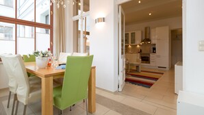 A modern kitchen with white cabinets, a stainless steel range hood, and a colorful rug.