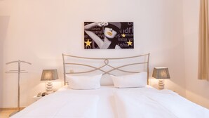 A neatly made bed with white linens, two bedside lamps, and a wall-mounted artwork above the bed.