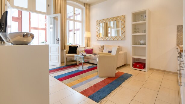 A modern living room with a sofa, coffee table, and a colorful striped rug.