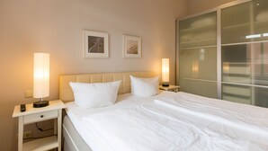 Una camera d'albergo con un letto grande, due comodini con lampade e due quadri appesi al muro.