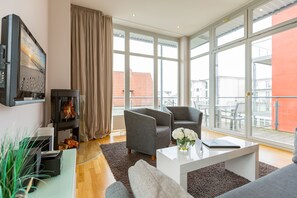 Een moderne woonkamer met een open haard, grote ramen en een balkon.