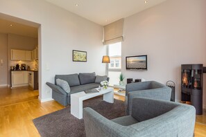 Ein modernes Wohnzimmer mit einem grauen Sofa, einem weißen Couchtisch und einem Kamin.