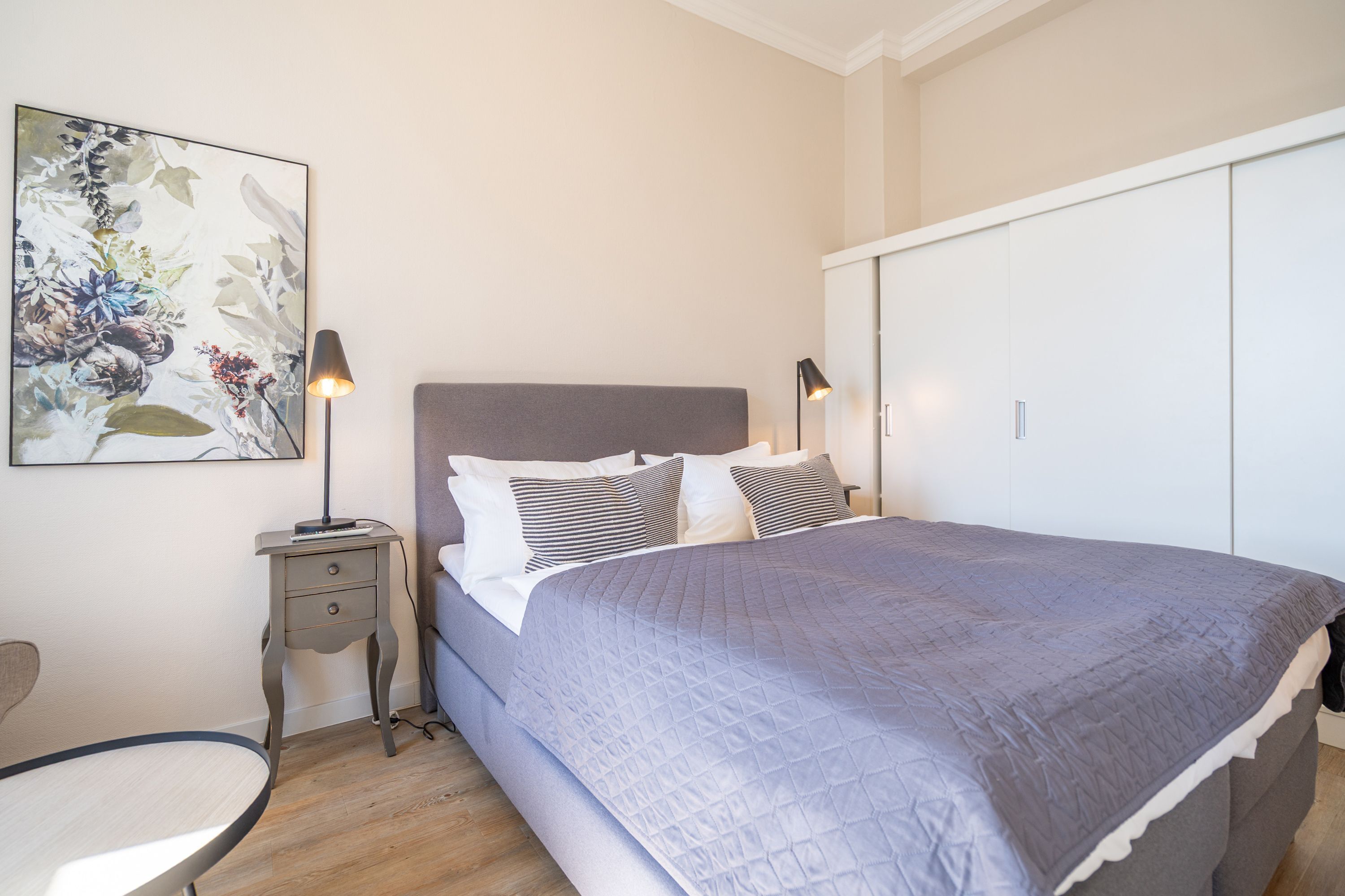 Une chambre à coucher comprenant un lit, des tables de chevet, une chaise et une armoire.