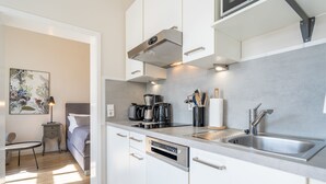 A modern kitchen with white cabinetry, stainless steel appliances, and a built-in dishwasher. - Villa Albertine, App. 07 (Heringsdorf)