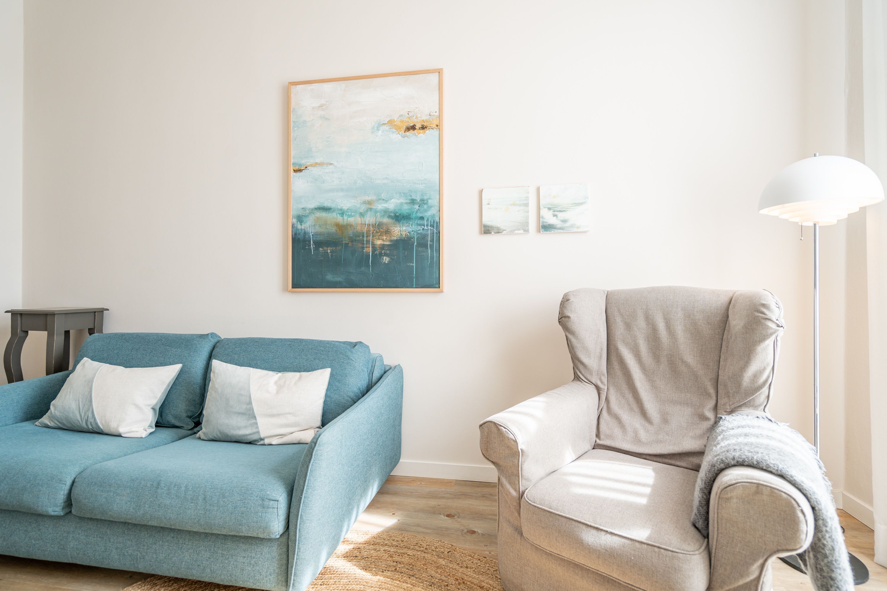 A living room with a blue sofa, a white armchair, and a floor lamp.