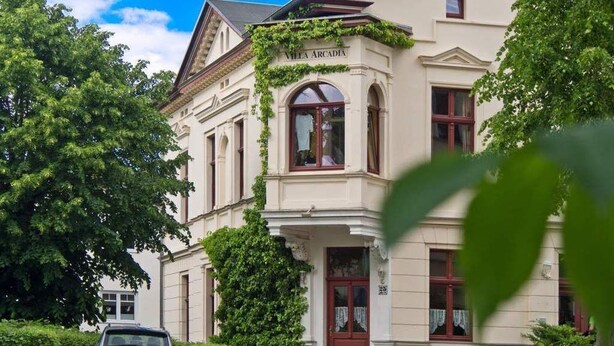 A historic building with a classic architectural style, featuring a prominent entrance with a red door and arched windows. - Villa Arcadia, App. 10 (Heringsdorf)