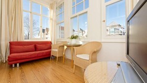 Een moderne woonkamer met een rode bank, een ronde salontafel en een televisie.