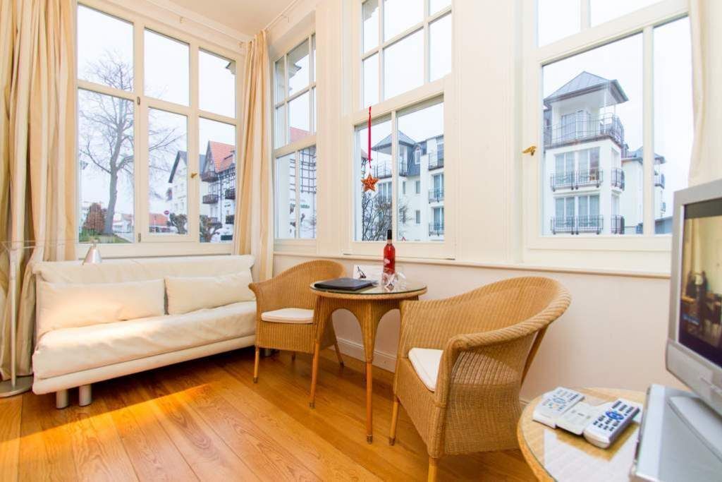 Une pièce comprenant un canapé, des fauteuils en osier, une petite table et un téléviseur.