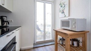 Eine Küche mit einer Mikrowelle auf einem Holztisch, einer Kaffeemaschine und einer Glastür zu einem Außenbereich.