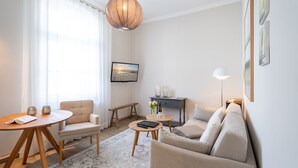 Ein modernes Wohnzimmer mit einem runden Holztisch, einem beigen Sofa, einem kleinen runden Tisch mit einem Laptop und einer Bank.