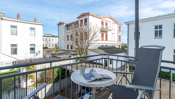 Ein Balkon mit Tisch, Stühlen und Blick auf umliegende Gebäude.