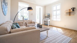 Un salón amplio con un sofá color crema, una mesa de centro y un mueble para televisión.