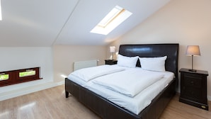 A bedroom with a skylight, a bed, a nightstand, a lamp, and a small wooden cabinet. - Villa Arcadia, apt. 07 (Heringsdorf)