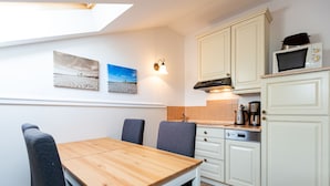 A compact kitchen with a dining table and chairs, a microwave, and a coffee maker. - Villa Arcadia, apt. 07 (Heringsdorf)