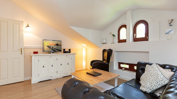 A cozy living room with a leather sofa, a wooden coffee table, and a white cabinet with a television. - Villa Arcadia, apt. 07 (Heringsdorf)