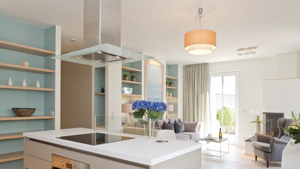 A modern kitchen with a central island, built-in oven, and a dining area with a sofa and table. - Dünenpalais, App. 01 (Heringsdorf)