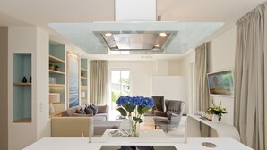 A modern living room with a white dining table, a sofa, and a TV. - Dünenpalais, App. 01 (Heringsdorf)