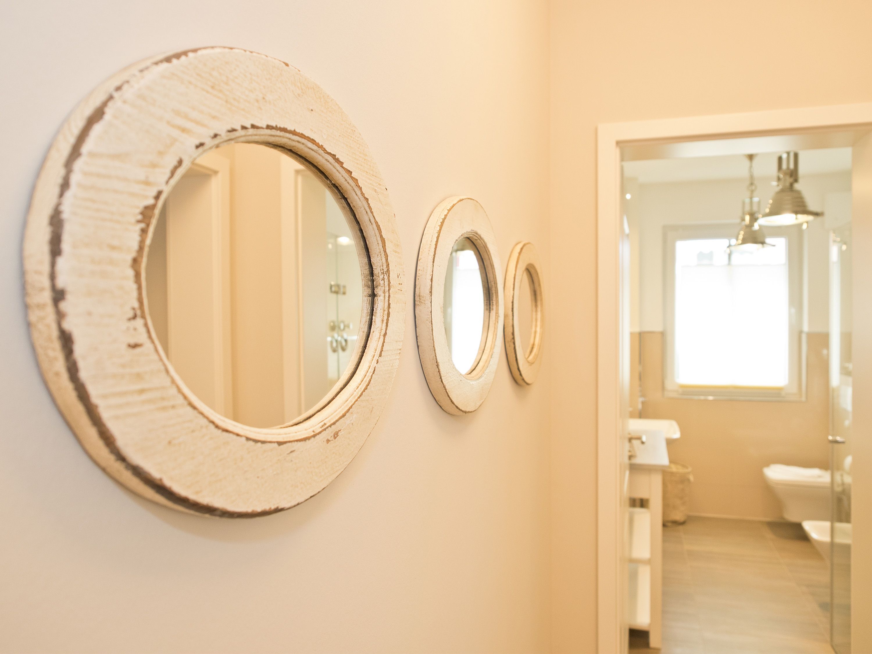 Three wall-mounted mirrors of varying sizes in a bathroom.