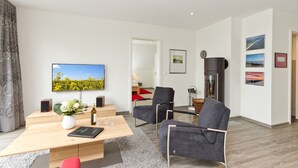 Un salon moderne avec une table basse en bois, un téléviseur à écran plat, un canapé et une table à manger avec des chaises.