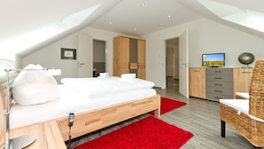 Une chambre moderne avec un lit en bois, un tapis rouge, une télévision et une armoire.