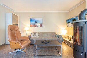 A modern living room with a leather armchair, a sofa, a coffee table, and a fireplace.