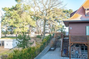 A building with a stone facade, a wooden deck, and a staircase leading to a second floor.