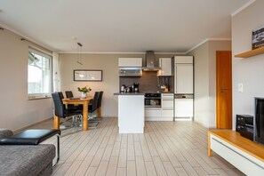 Uma cozinha moderna com armários brancos, uma ilha central e um espaço de jantar com mesa e cadeiras.