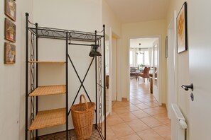 Un couloir avec une étagère en métal, un panier en osier et un radiateur.