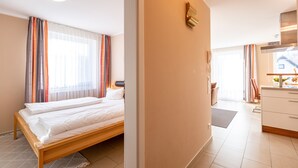 A hotel room with a bed, a desk, and a kitchenette.