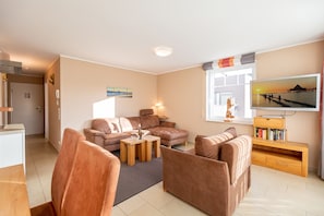 A modern living room with a sofa set, a coffee table, and a TV on a wooden stand.