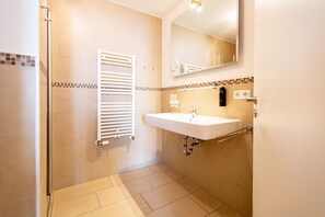 Une salle de bain avec un lavabo blanc, un miroir et un porte-serviettes.