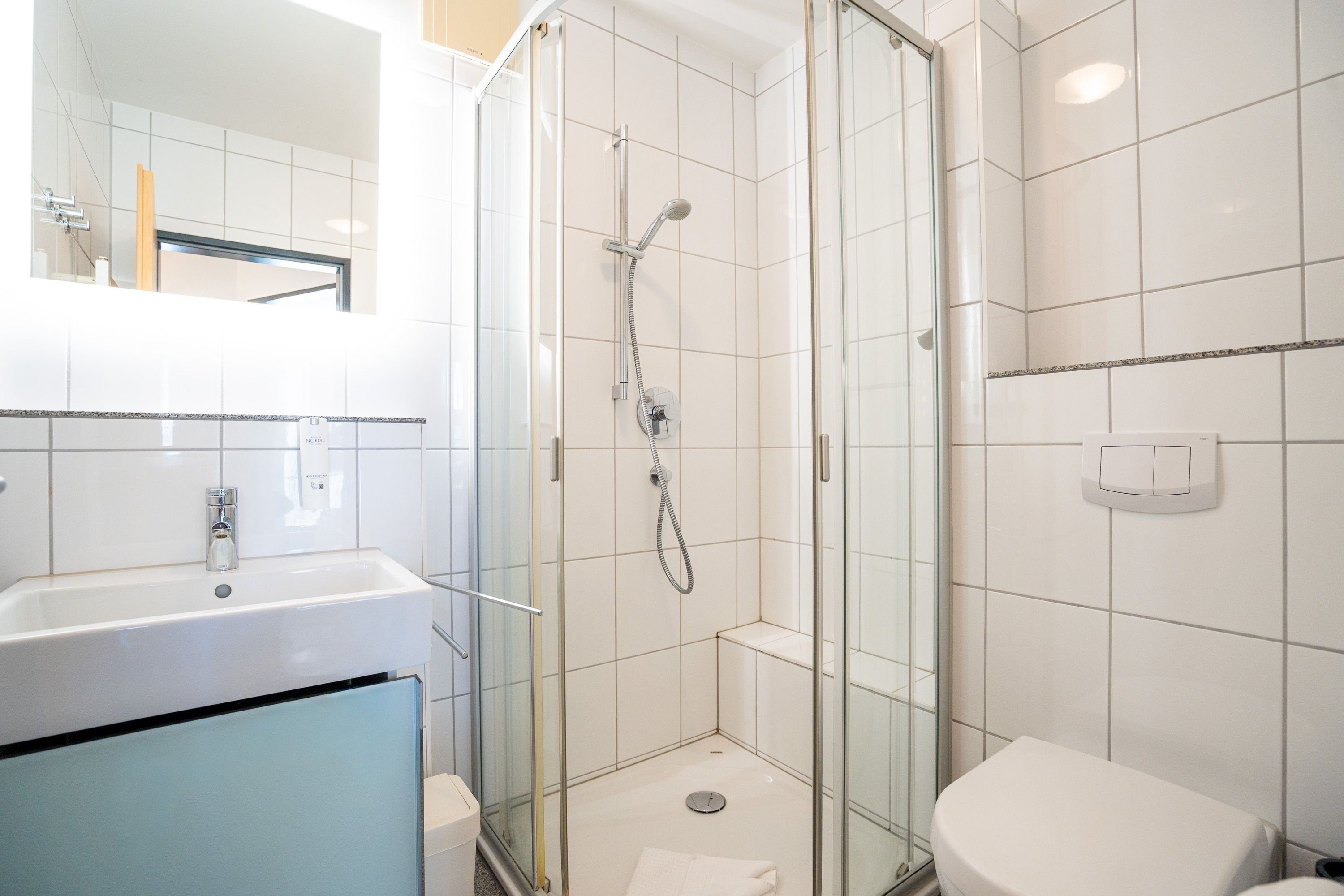 A modern bathroom with a glass-enclosed shower, a white sink, and a toilet.