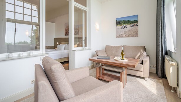 A modern living room with a sofa, a coffee table, and a window overlooking a beach scene.