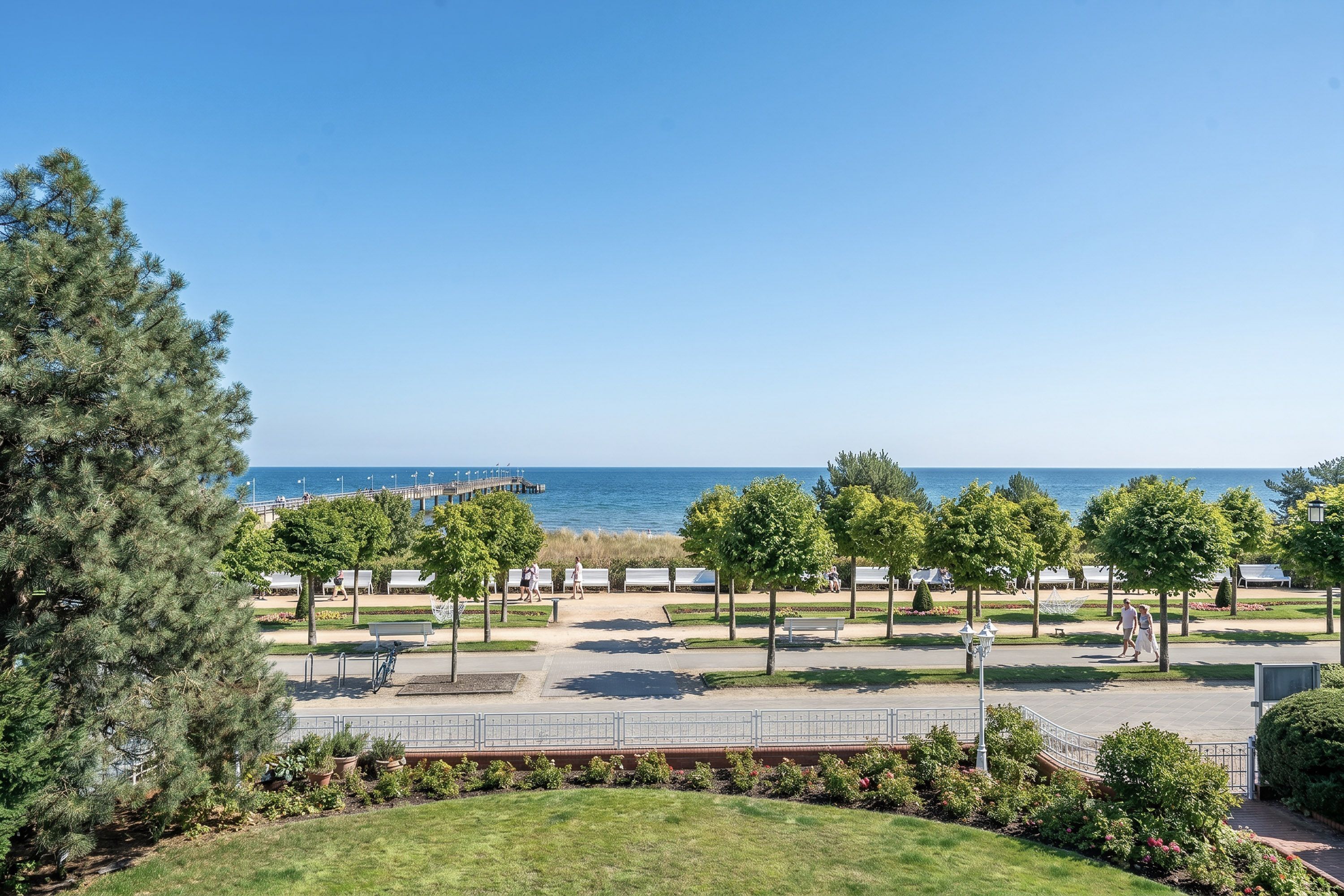 A park with pathways, benches, and trees, overlooking a body of water.