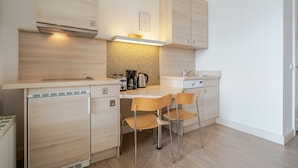 A compact kitchen with a dishwasher, a coffee maker, and a sink.