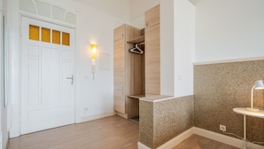 A modern room with a white door, wooden flooring, a built-in wardrobe, and a granite accent wall.