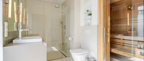 A modern bathroom with a glass shower enclosure, a white toilet, and a wooden door.