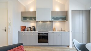 Una cocina moderna con armarios grises, horno empotrado y microondas.