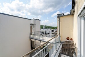 A residential building with a balcony, a view of neighboring houses, and a clear sky.