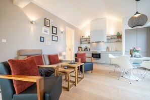 Un salon moderne comprenant un canapé, des fauteuils, une table basse et un coin repas avec des chaises et une table.