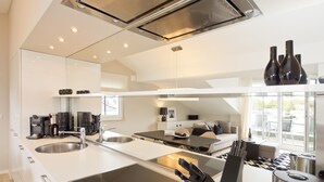 Una cocina moderna con una isla central, electrodomésticos de acero inoxidable y un comedor con sofá y mesa.