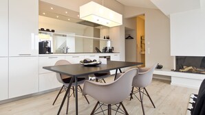 Una cocina moderna con armarios blancos, una mesa de comedor con cuatro sillas y un horno empotrado.