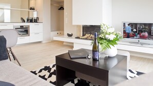 Una sala moderna con una mesa de centro negra, un sofá y un televisor.