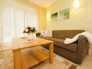 Una sala de estar con una mesa de madera, un sofá marrón y un jarrón de flores.
