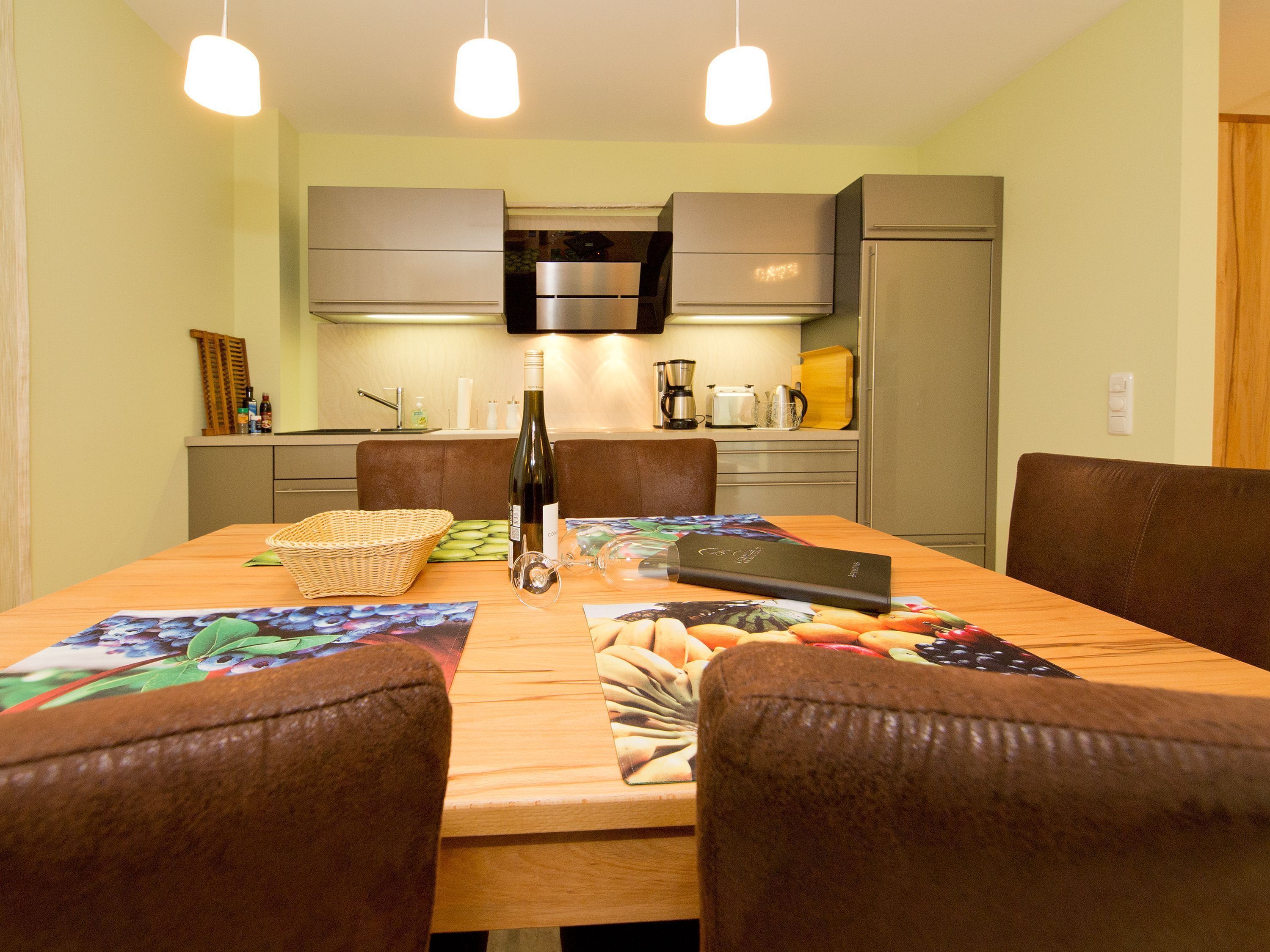 A dining area with a wooden table, chairs, and a bottle of wine.